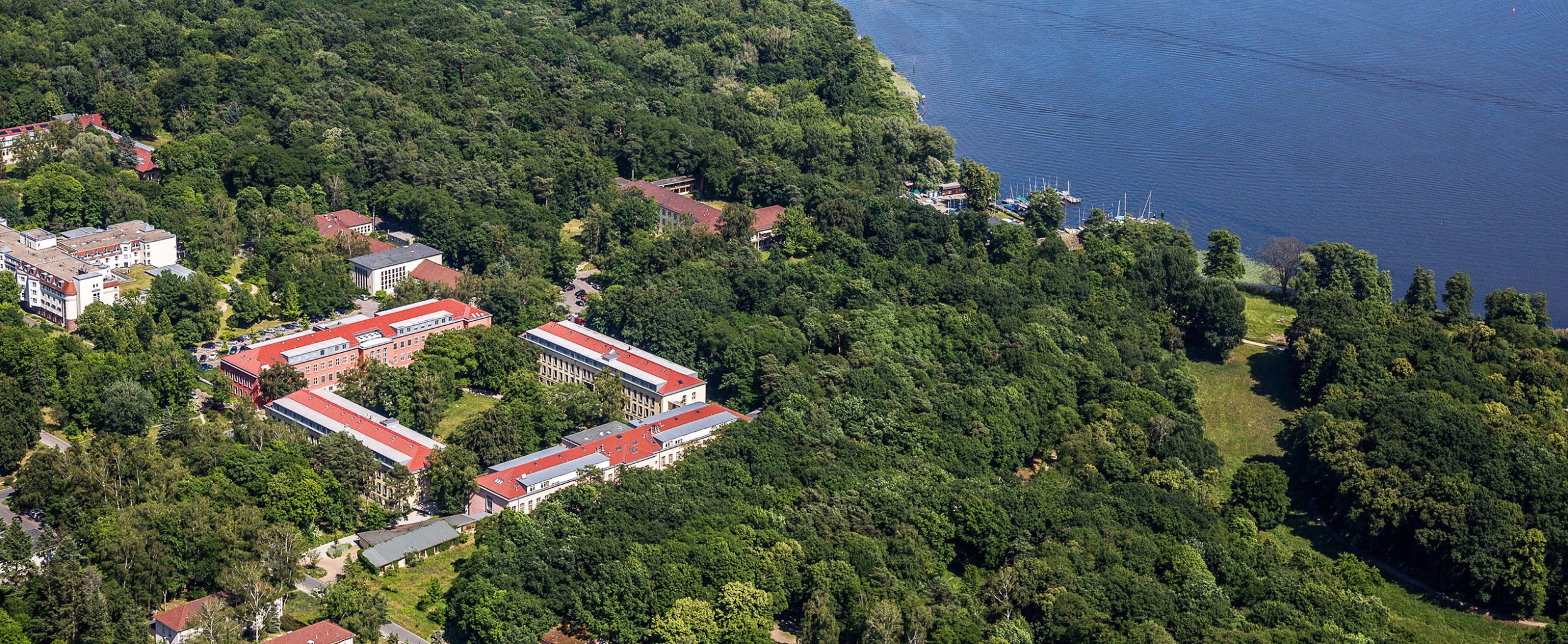 Luftaufnahme vom Gemeinschaftskrankenhaus Havelhöhe umgeben von Wald, Wiesen und Wasser